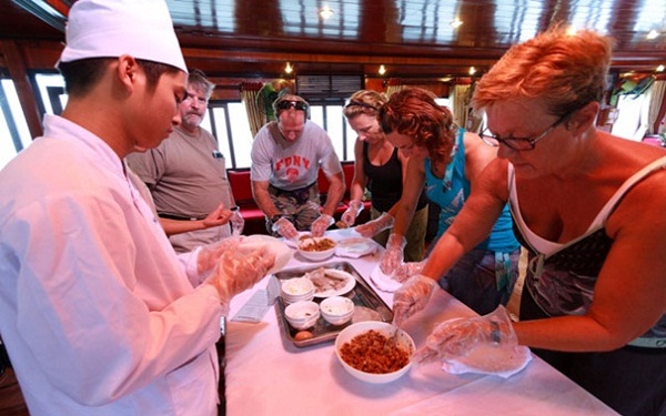 Travellers learning how to cook Vietnamese food in a cooking class on boat