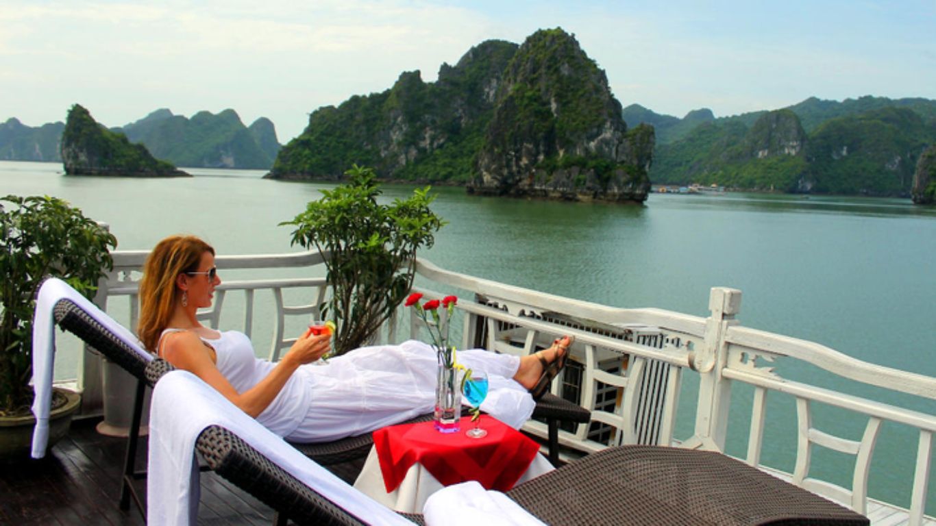 A woman relaxing with a drink on the sundeck of a Halong Bay junk boat cruise